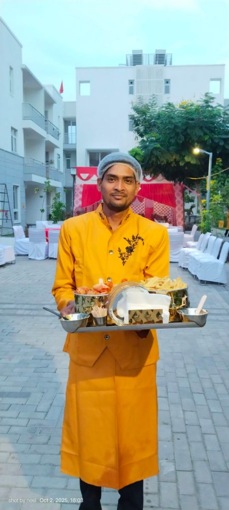 Mithila Events server in yellow uniform and hairnet carrying a tray of starters at a society lawn event
