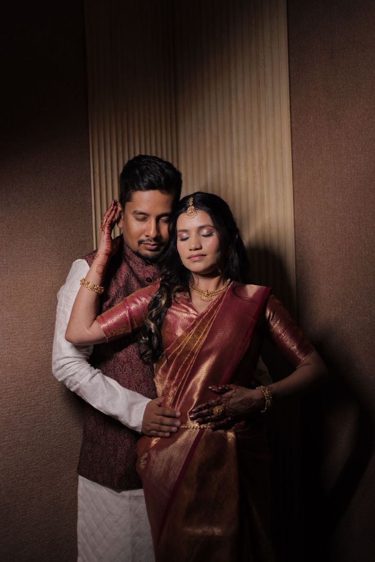 Close portrait of a couple, the bride in a maroon silk saree with mehendi on her hands