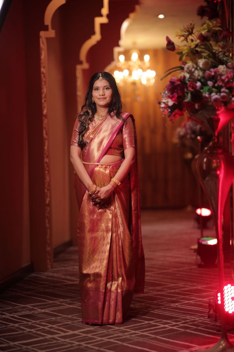 Woman in a green and red saree photographed against neon lights at an evening function in Noida