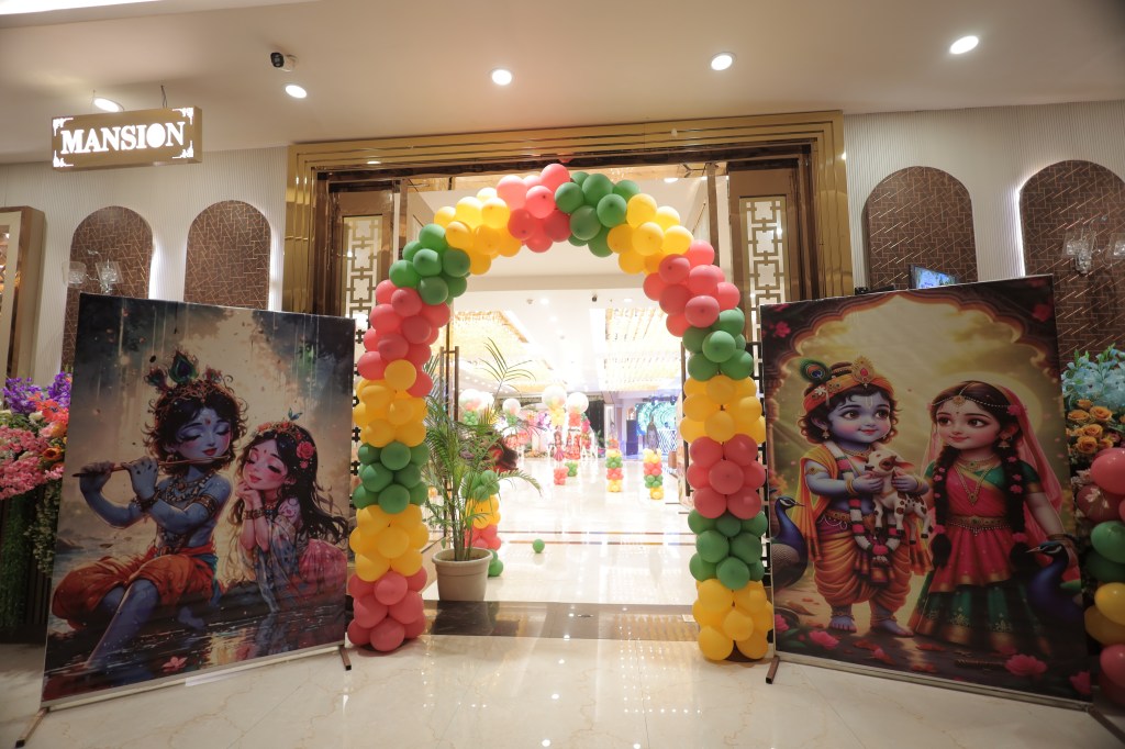 Colourful balloon arch at a banquet hall entrance for a Krishna theme first birthday in Noida