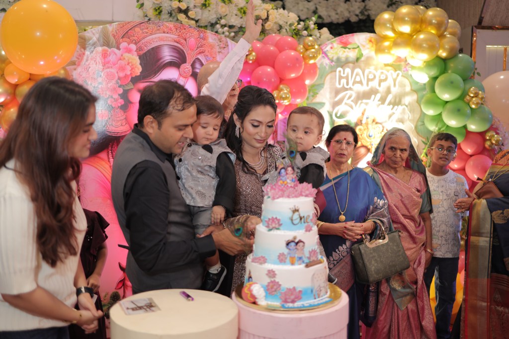 Parents and family cutting the cake with the twins at a Krishna theme first birthday in Noida