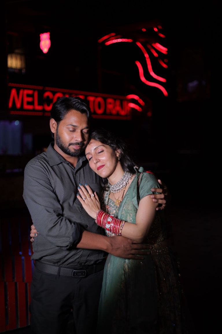Couple embracing under red neon signage during an evening pre-wedding shoot in Noida