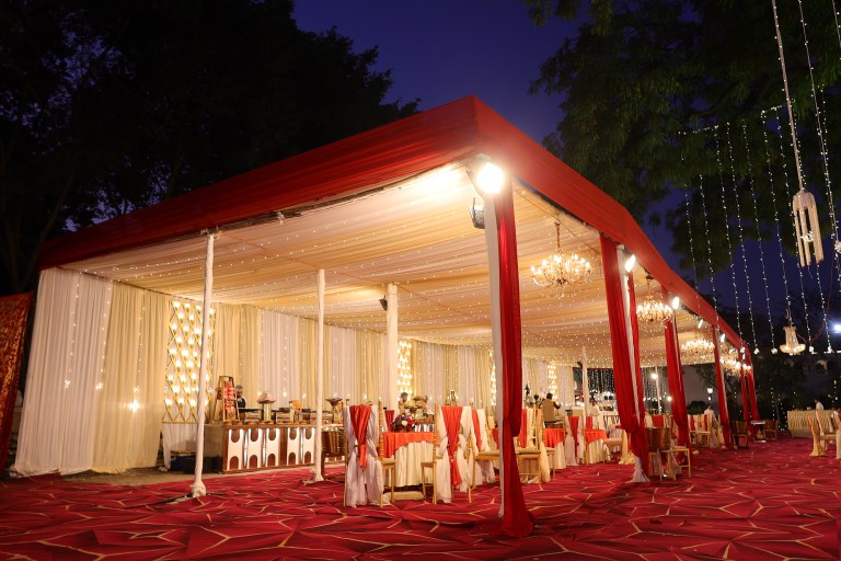 Tented guest seating with red and cream drapes at a farmhouse wedding