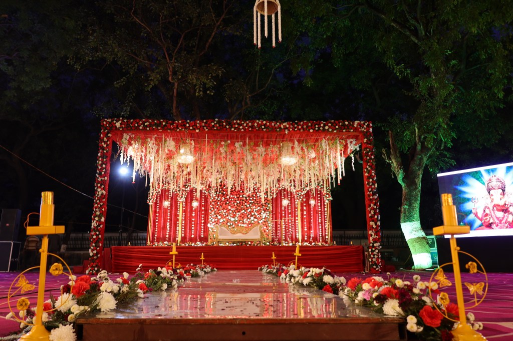 Red and gold draped wedding mandap stage decorated by Mithila Events in Noida