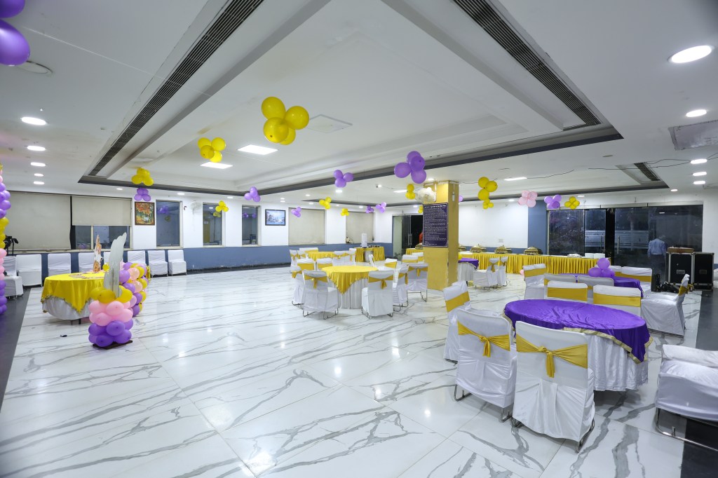 Wide view of a birthday banquet hall decorated with gold and purple balloons by Mithila Events