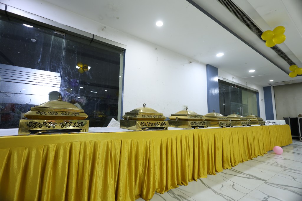 Buffet counters with gold skirting and chafing dishes at a birthday party banquet by Mithila Events